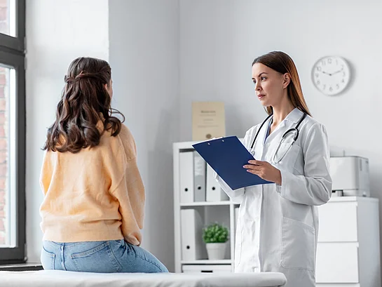 Dermatologe untersucht Patientin mit Neurodermitis